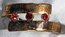 Goldfarbener Ring (D 1,8 cm, 1 cm breit) mit drei roten Steinen